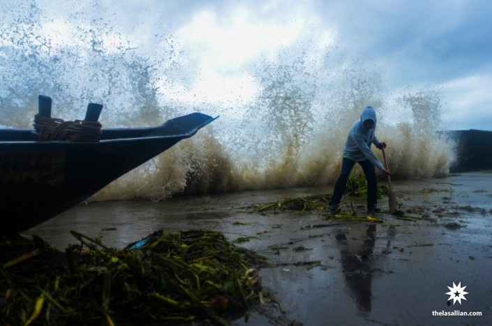 A man from a community by Laguna Bay tries to clear the shore as the area faces the winds and rain of super typhoon Yolanda during the peak of the tempest in November 2013.